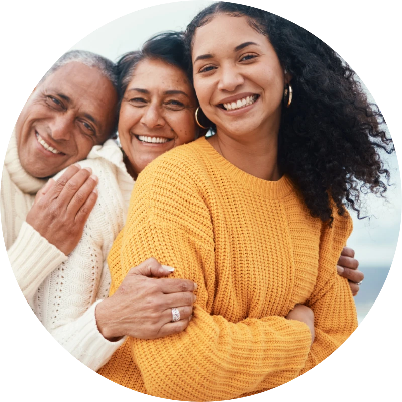 Three family members hug and smile.