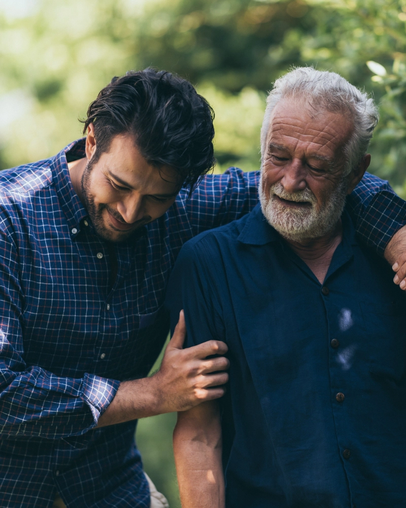 An older man and his son walk together in nature.