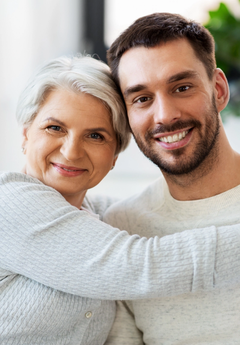 A young man and his mom smile together.